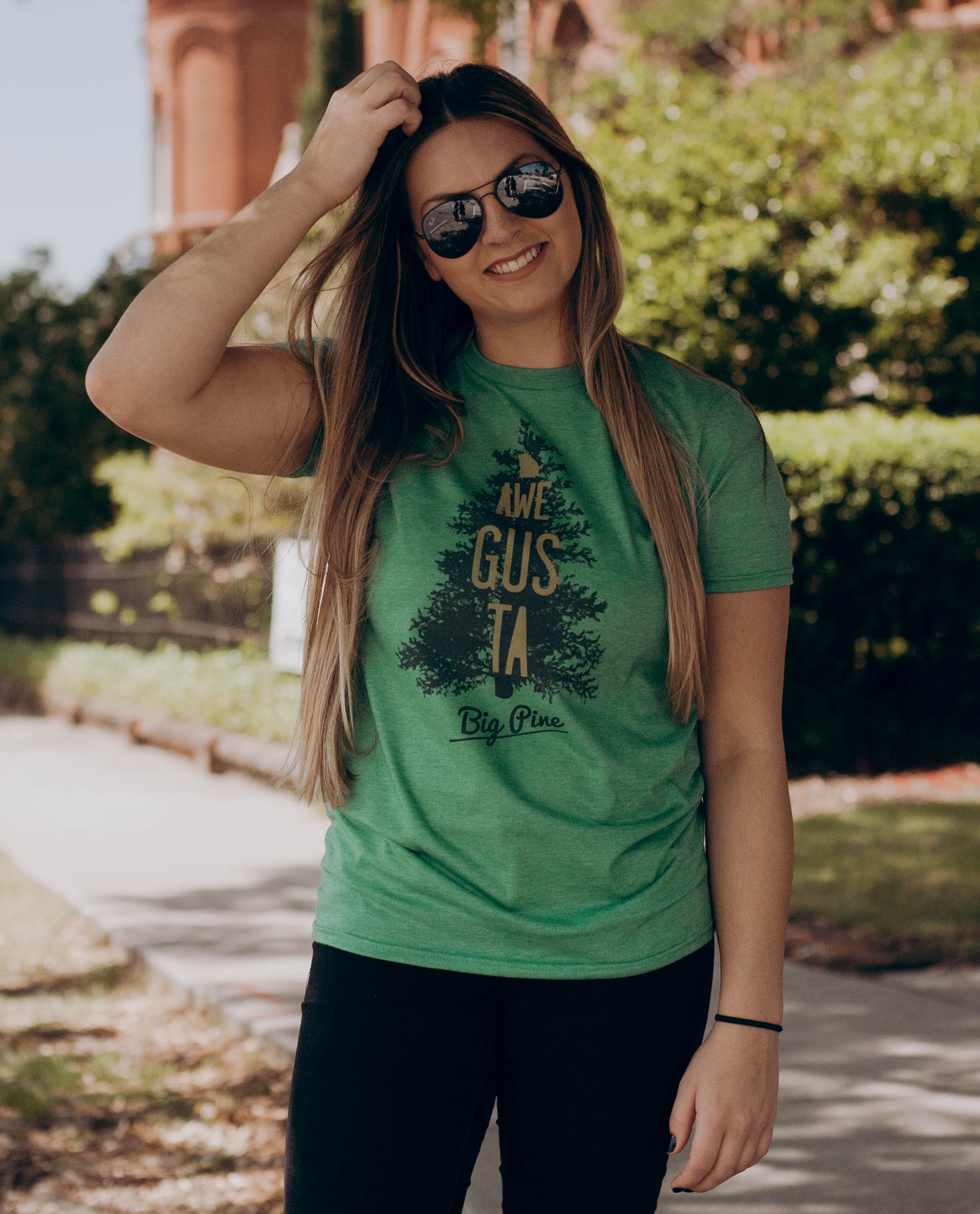 Woman in sunglasses wearing green Awe Gus Ta shirt