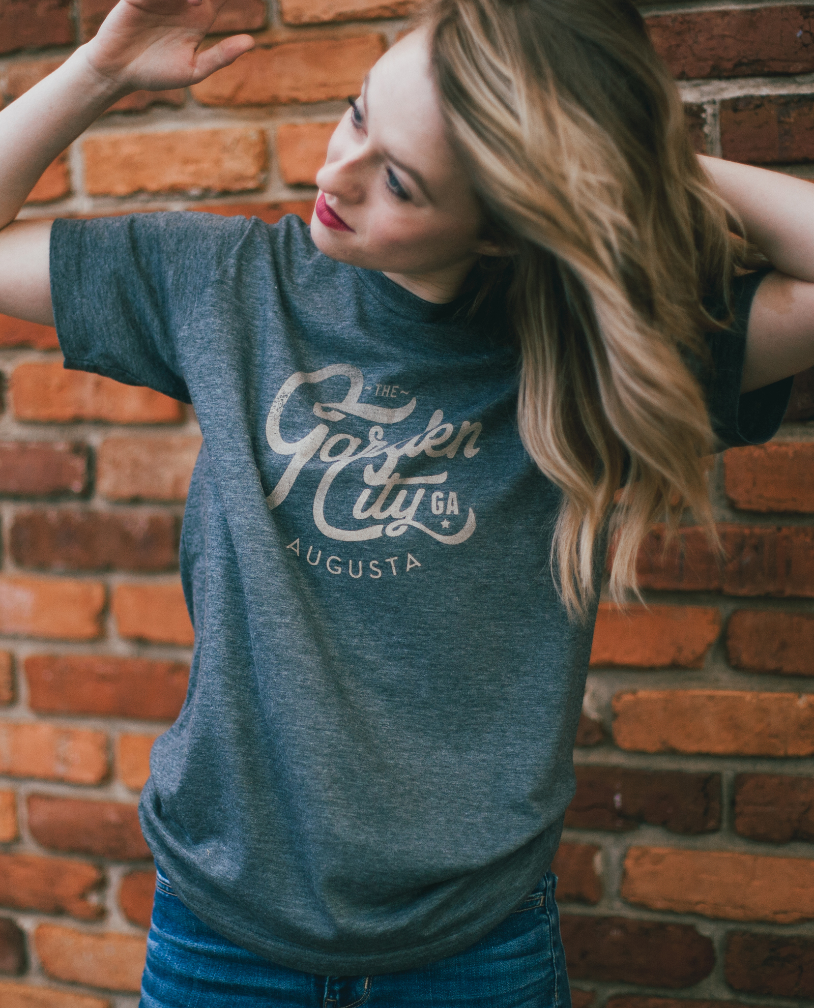 Woman in front of brick wall wearing blue vintage Garden City shirt