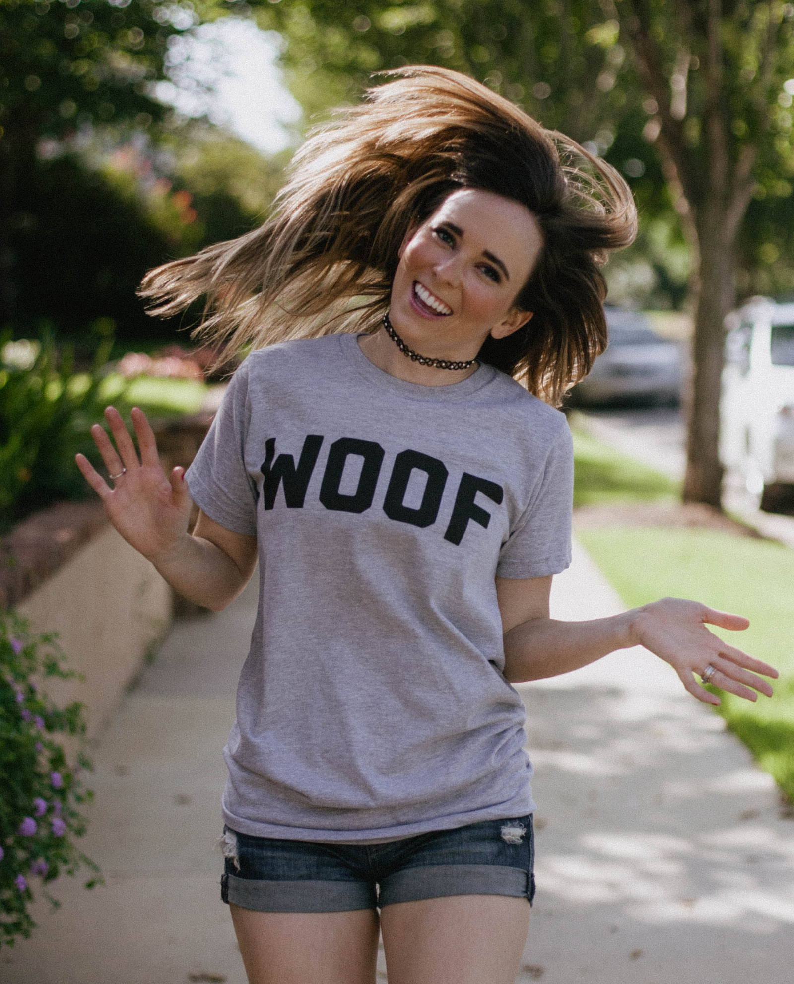 Woman flipping hair and wearing gray WOOF shirt