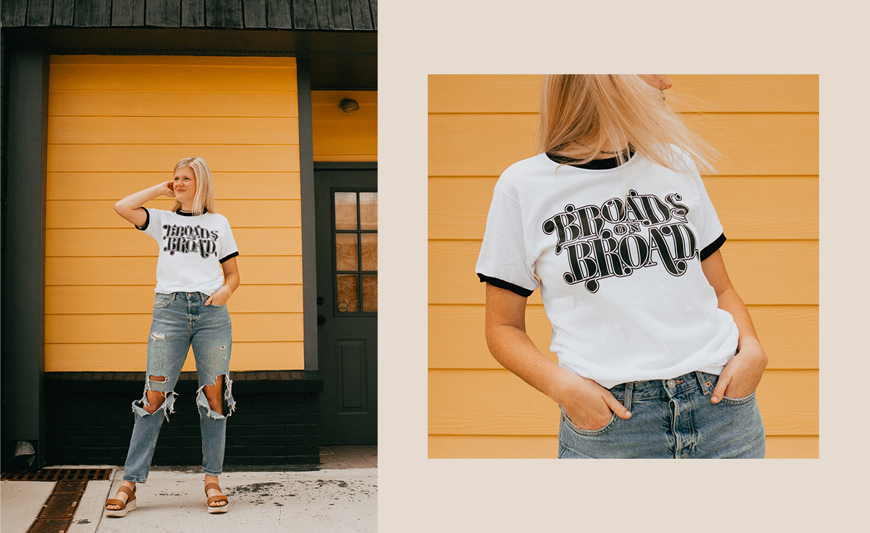 Woman in ripped jeans standing in front of yellow wall wearing Broads on Broad shirt