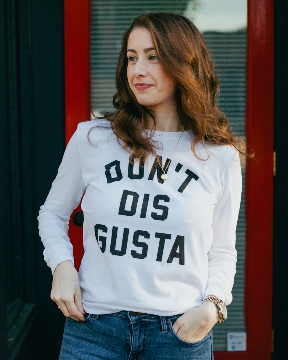 Woman wearing white long sleeve Don't Dis Gusta shirt with jeans