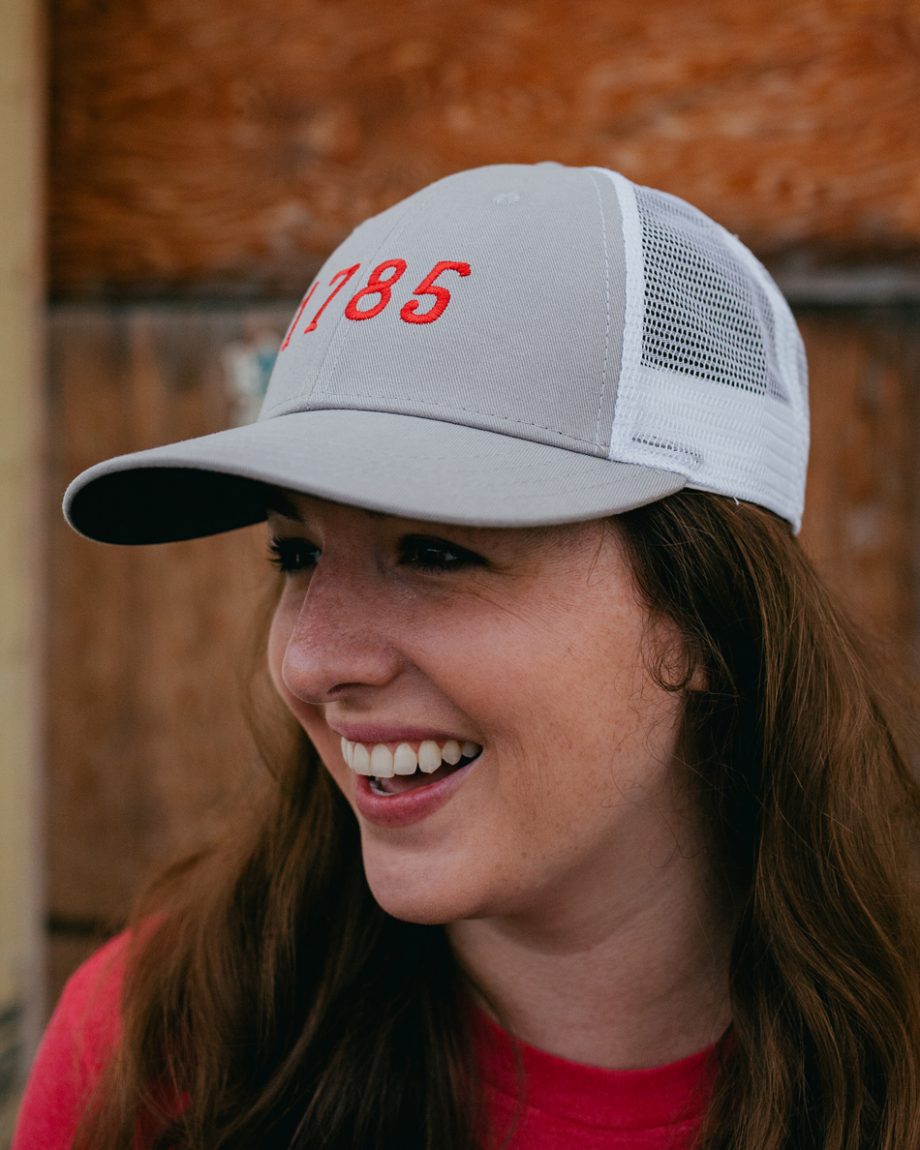 Woman wearing gray and red 1785 Athens Georgia trucker hat
