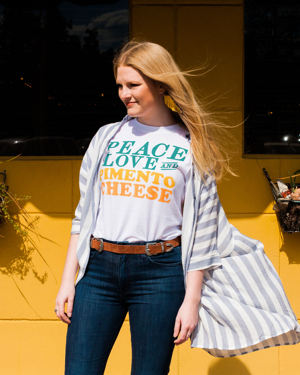 Woman wearing white Peace Love and Pimento Cheese shirt with jeans